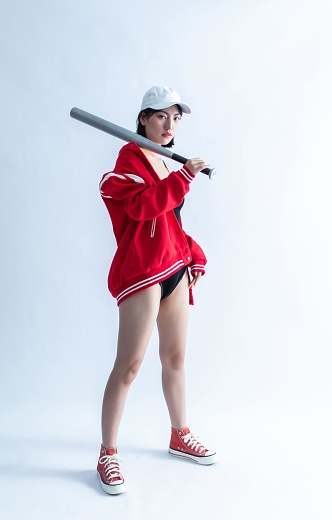 Asian woman in red jacket and white cap holding a baseball bat