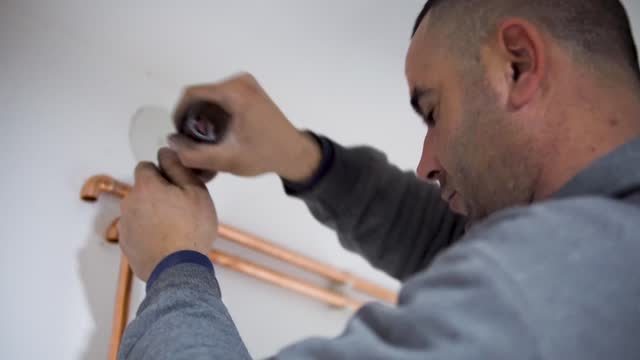 Plumber cutting a copper pipe with a pipe cutter stock video