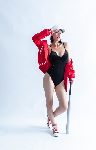 Asian woman in red bomber jacket and black swimsuit holding a baseball bat