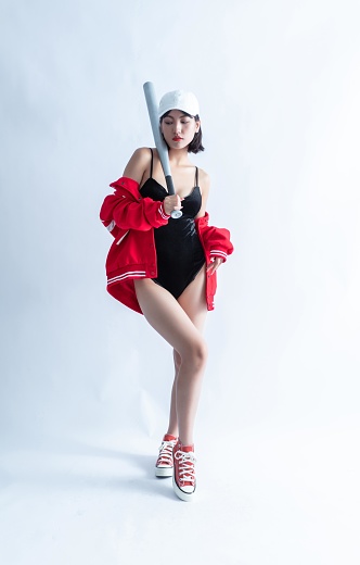 Asian woman in red bomber jacket and black swimsuit holding a baseball bat