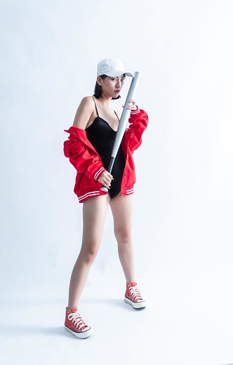 Asian woman in red bomber jacket and white cap holding a baseball bat