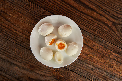 Soft boiled eggs on a plate on a wooden board, flat lay studio shot