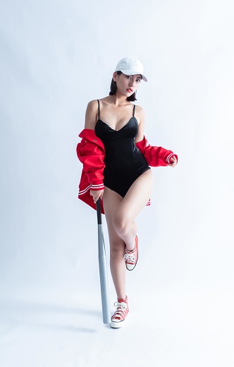 Asian woman in red bomber jacket and black swimsuit holding a baseball bat