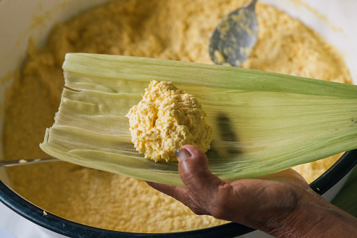 Hands of an unrecognizable woman preparing a traditional Peruvian corn meal called Humita