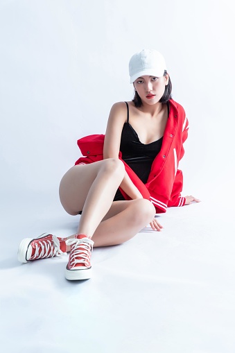 A Young Asian Woman Wearing a Red Bomber Jacket and White Cap Posing on the Floor