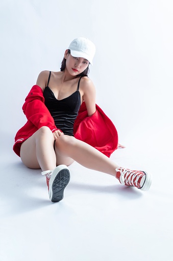 A Young Woman Wearing a Cap, Swimsuit, and Red Jacket Posing on the Floor