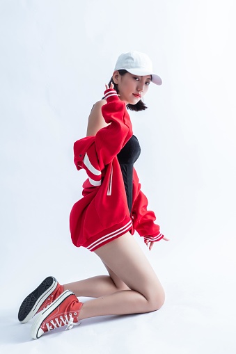 A young woman with a white cap and red jacket is posing on one knee