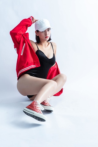 A woman in a red jacket and black swimsuit poses on the floor