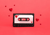 Cute red analog cassette on red background with reds hearts flying around.