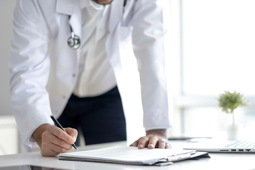 unrecognized doctor signing documents at the table