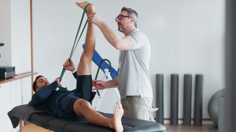 Physiotherapy, man and stretching muscle in legs with a resistance band, equipment or healing exercise with therapist. Physical, rehabilitation and patient training with support of physiotherapist