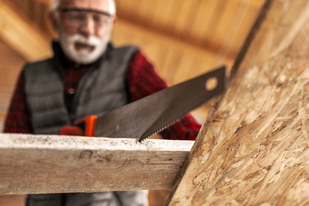 Senior male craftsman at his workshop sawing wood
