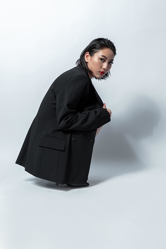 Asian woman in black suit crouching