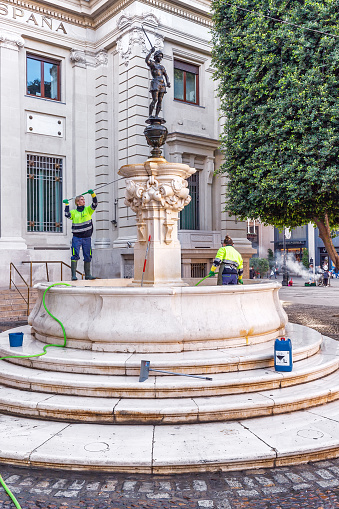 Seville, Spain - December 20, 2023: Cleaners wash a beautiful fountain in the center of Seville
