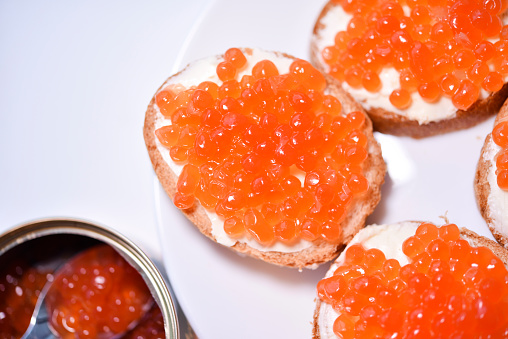 Red salmon caviar on bread and butter. A spoon with red caviar.