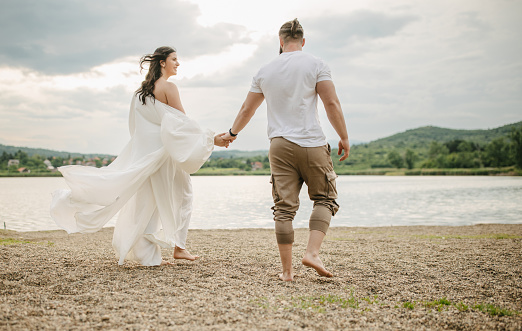 Happy young couple walking by the lake outdoors.