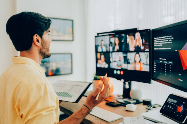 istock Man at standing desk home office talking on business video call 1955446299