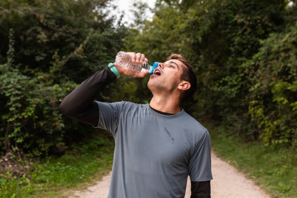 istock Hydration Break: A Jogger Refreshing with a Water Bottle on a Forest Trail 1955449400