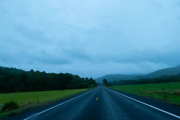 An open empty road through a stormy landscape and beautiful mountains.