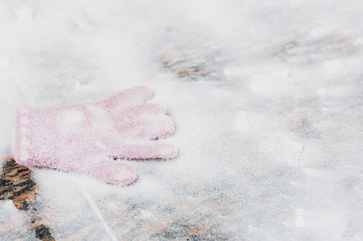 pink glove under the snow on a stone pedestal