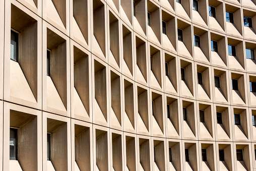 The Housing and Urban Development (HUD) Building in DC is an example of brutalist architecture. The name of this style comes from the French term, béton brut, which simply means “raw concrete.” The idea, very popular among architects in the 1950s-1970s, was that concrete was not simply a structural material, but should be exposed on the outside of the building. 

Personally, I think the English term, “brutalism,” describes this now out-of-fashion style very well. 

On the other hand, at times, this kind of architecture, or at least parts of a brutalist building, can yield interesting abstract patterns. Here, we see the building abstracted by a pattern of arcs of circles and dark trapezoids.