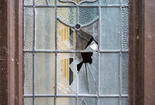 Smashed glass in the glazed section of a door in a derelict public house.