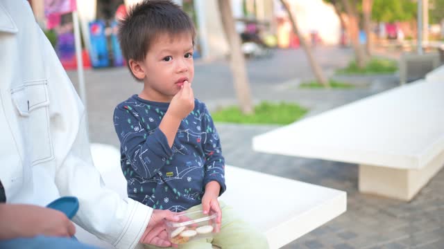 Sweet moments on the boardwalk: Multiracial toddler enjoys snack with mom