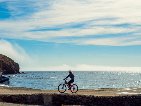 Isleta del Moro, Nijar, Spain. 01/23/2024. Young girl riding a bicycle along a pier on the coast of Cabo de Gata, Almeria.