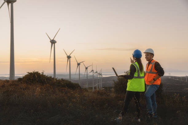 istock Young maintenance engineer team working in wind turbine farm at sunset 1955493914