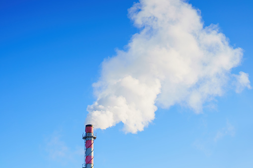 White smoke from a chimney on the background of a blue sky