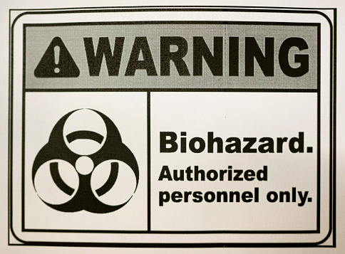 Close-up of a biohazard warning sticker on a door for authorized personal only in a medical laboratory