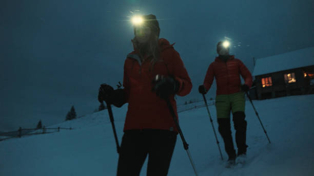 istock Young couple hike through snow at night 1955583247