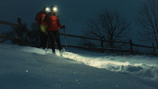 istock Young couple hike through snow at night 1955583258