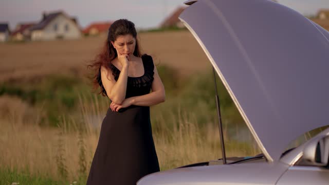 Woman open car hood and check up engine waiting for master service, standing on rural country side
