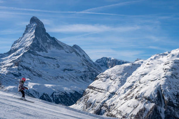 Young girl skis down ski slope on sunny day below the Matterhorn mountain