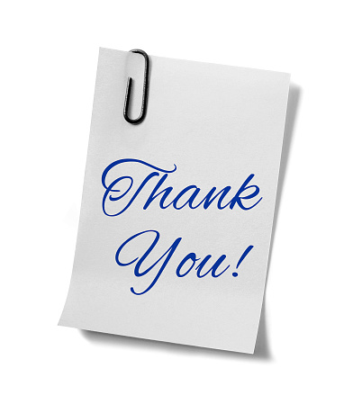 'Thank you' written on a paper note held with a paper clip. Isolated on a white background.