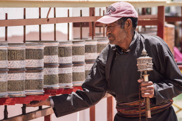 Old woman holding hand prayer wheel and prayer beads