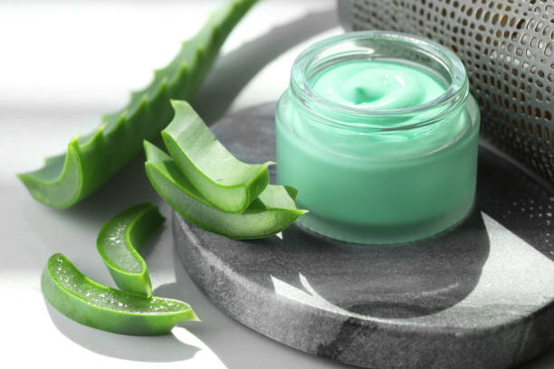 istock Jar with cream and cut aloe leaf on white table, closeup 1955625669