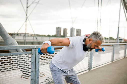 Senior man having outdoor training with weights