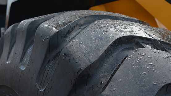 Close-up of a large loader wheel with small pieces of ice on it