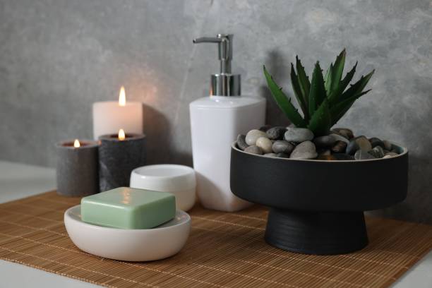 istock Potted artificial plant, soap, burning candles and bamboo mat on white table 1955689643