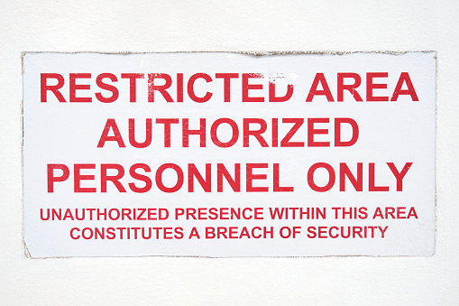 Restricted area authorized personnel only sign on white background. White weathered restricted area sticker with red text.