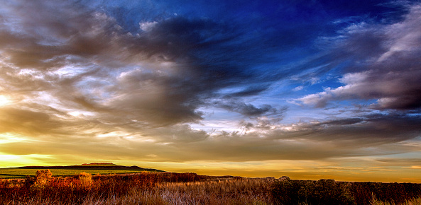 The sunrise in southern New Mexico creates a tranquil, beautiful and peaceful scenic.  The San Pascual Mountains are seen in the background with the green pastureland and the autumn colors contrasting with the stunning clouds and sky.