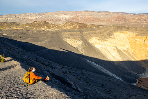 Captured on the rim of Ubehebe Crater in Death Valley National Park, young woman gazes into the heart of this ancient volcanic field