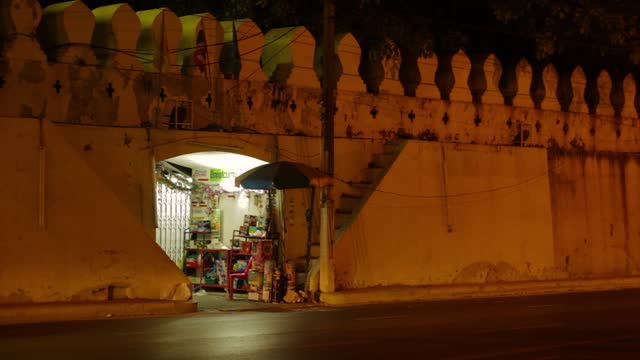 Evening Bustle: Illuminated Shop in Historical Archway with Passing Scooter
