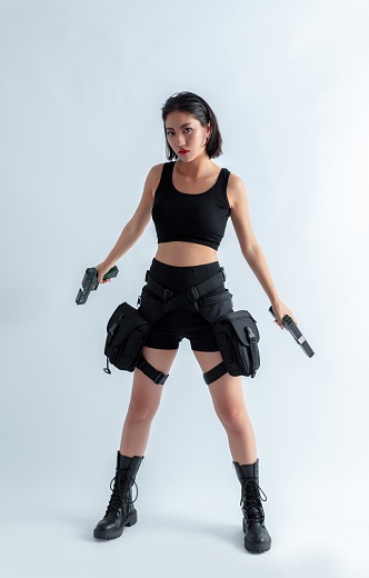 Asian woman in black tactical gear holding guns