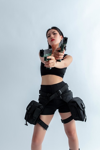 Asian woman holding two guns
