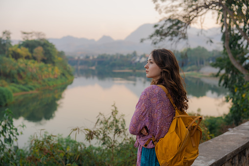 Serene woman walking on bridge looking at Mekong  river at sunset