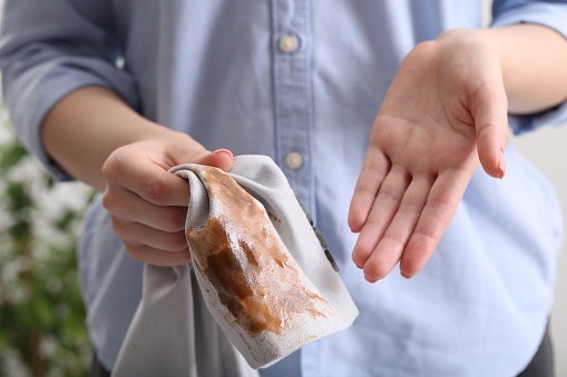 Woman showing stain from coffee on jacket against blurred background, closeup