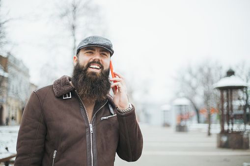 handsome hipster guy talking on the phone in the city on the street